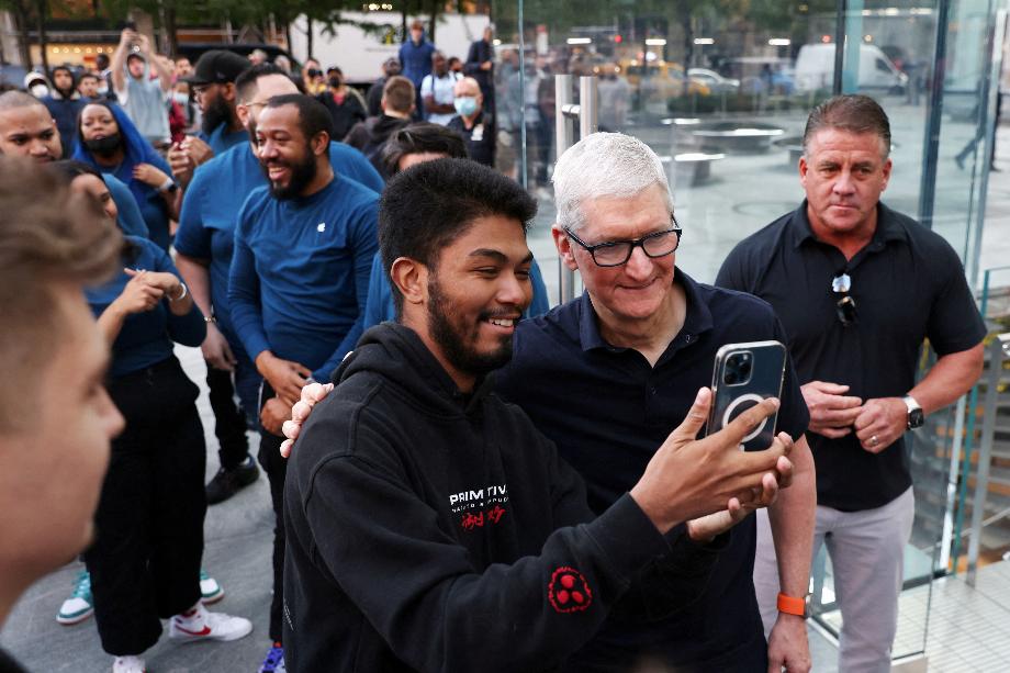 Le PDG d'Apple, Tim Cook, prend un selfie avec un client lorsqu'il entre dans le magasin Apple Fifth Avenue pour la sortie de la gamme Apple iPhone 14 à Manhattan, New York, États-Unis, le 16 septembre 2022. REUTERS/Andrew Kelly